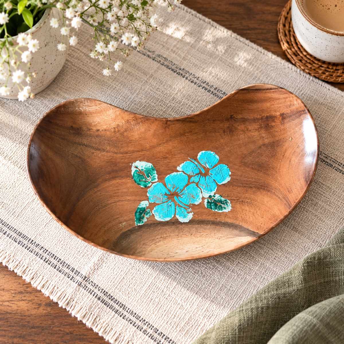 Bean-shaped wooden tray with hand-painted blue flowers on a woven table setting. hoWme