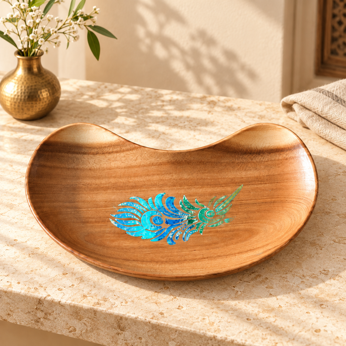 Bean-shaped wooden tray with blue-green peacock feather motif styled on a table. hoWme