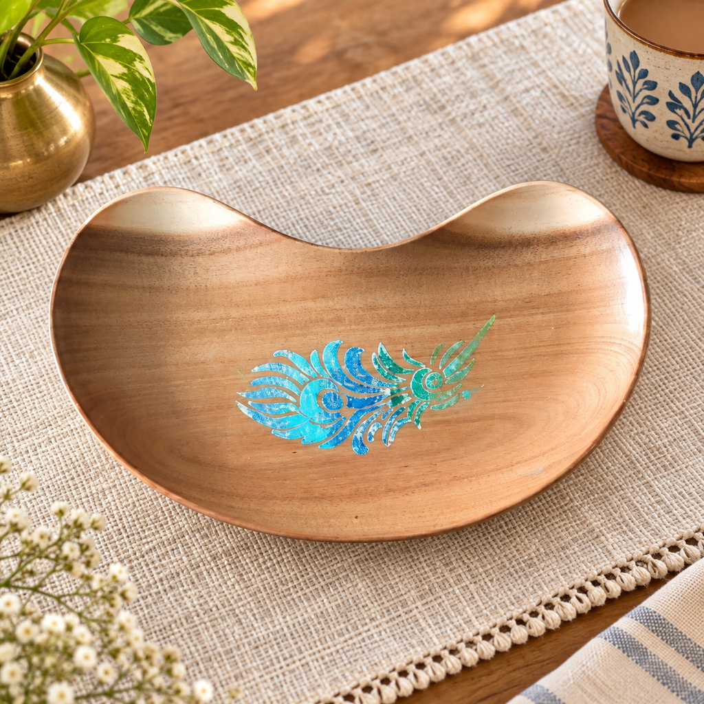 Bean-shaped wooden tray with blue-green peacock feather motif on a woven table setting. hoWme