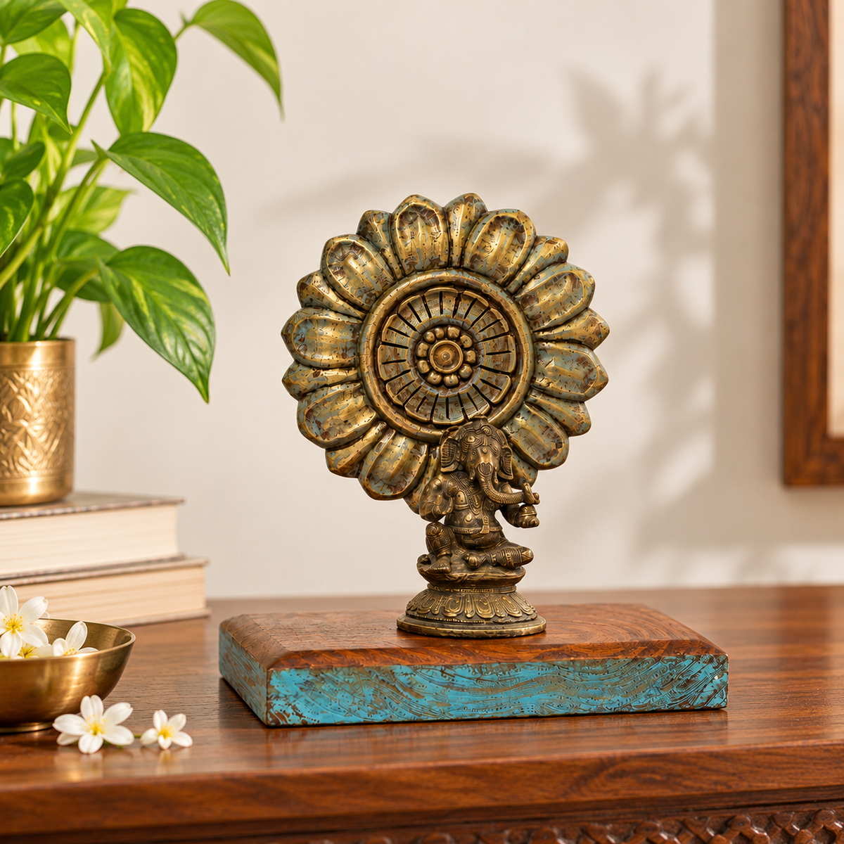 Brass Ganesha on a carved wooden base styled on a table with a plant. hoWme