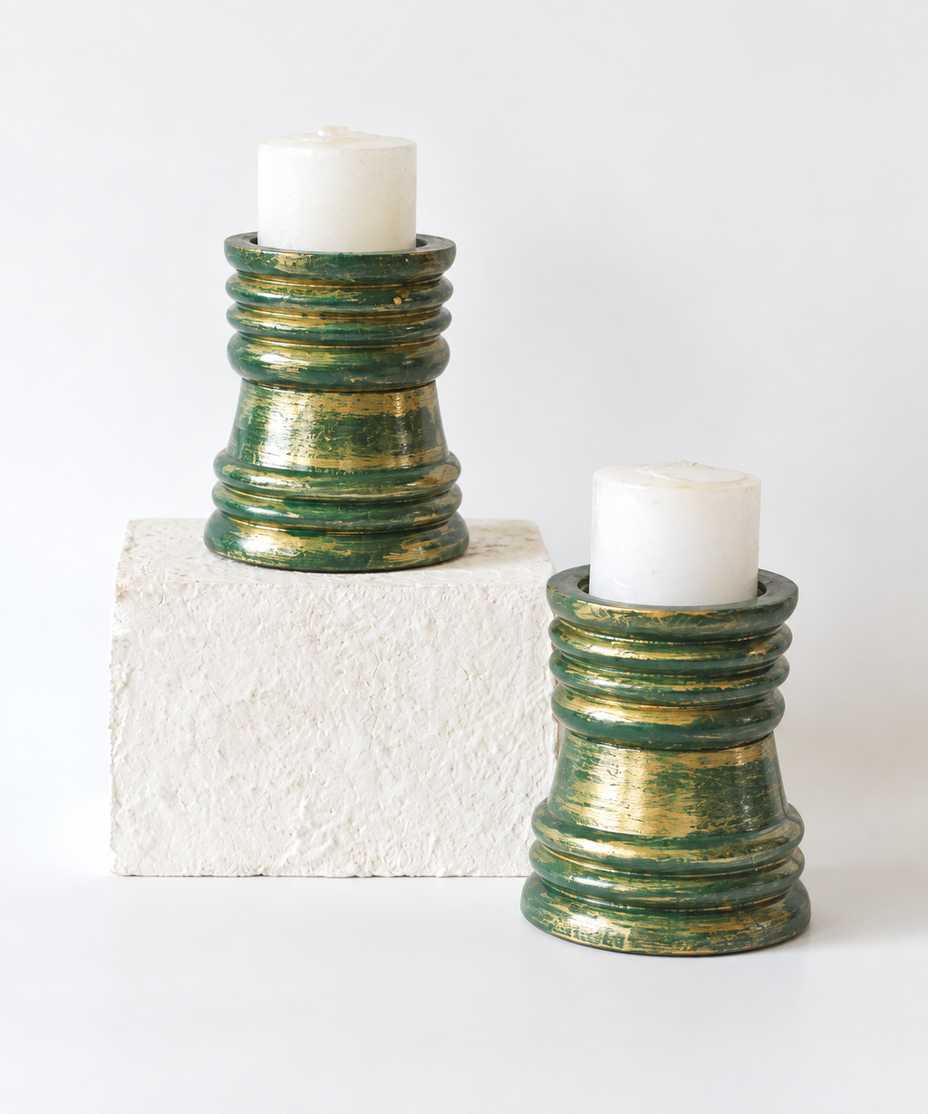 Green and gold wooden candlestands shown with white candles, hoWme.