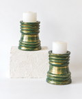 Green and gold wooden candlestands shown with white candles, hoWme.